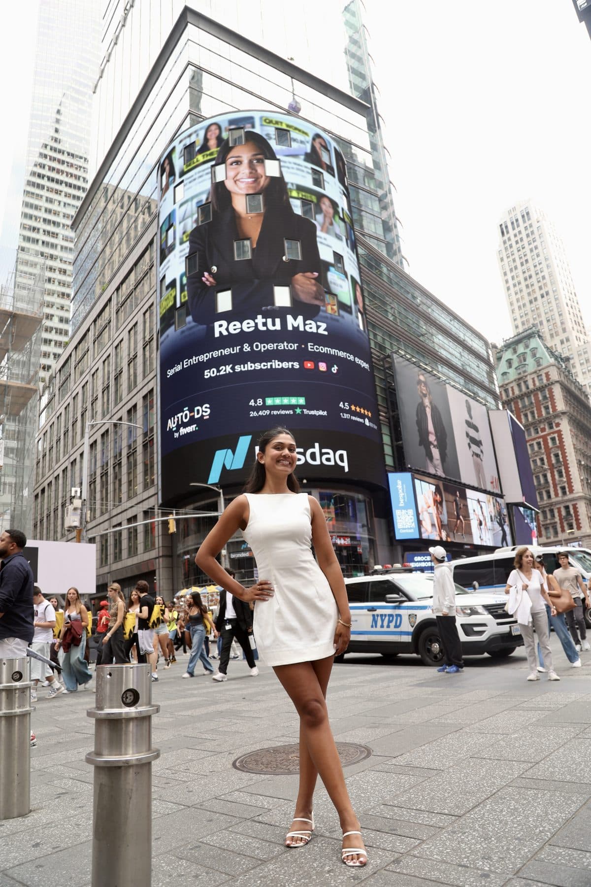 Reetu Maz standing beneath a Times Square billboard featuring her